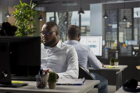 Multiethnic work team reviewing analytics and forecasting on computers Stock Photos