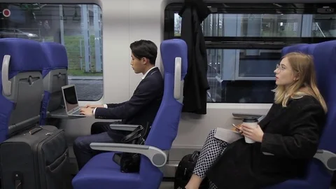The multiethnical people are sitting in train which is standing on the station. Stock Footage 84256782