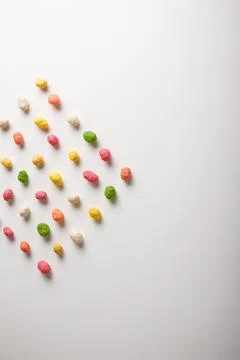 Multiflavored peanuts in bright multicolored icing on white table background. Stock Photos