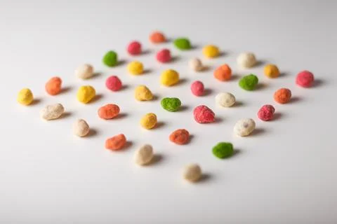 Multiflavored peanuts in bright multicolored icing on white table background Stock Photos