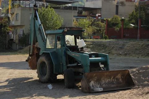 Multifunctional dark green tractor on construction site  Stock Photos
