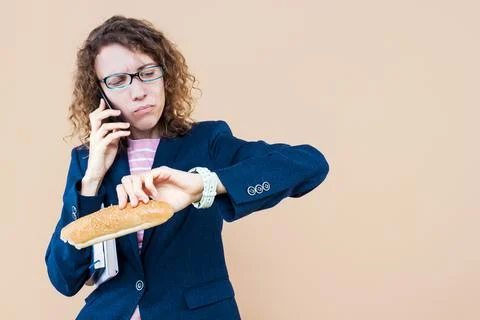 Multifunctional, multitasking business lady is talking on phone, eating on go Foto stock