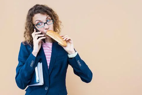 Multifunctional, multitasking business lady is talking on phone, eating on go Stock Photos