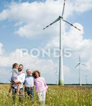 Multigeneration family standing on field on wind farm. Stock Photos