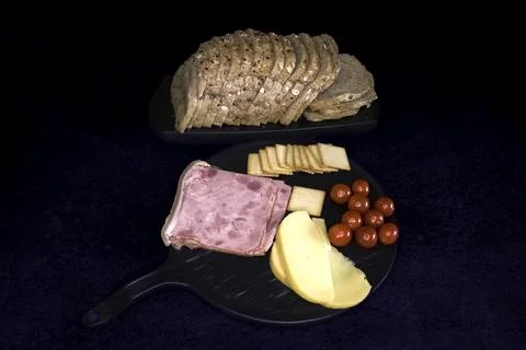 Multigrain bread, cheese, cherry tomatoes, salami, crackers arranged in dar.. Stock Photos