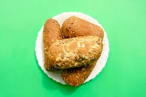 Multigrain mini bread in white plate on green background Stock Photos