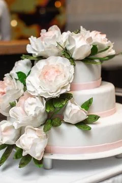 Multilevel wedding cake on the table decorated with roses Stock Photos