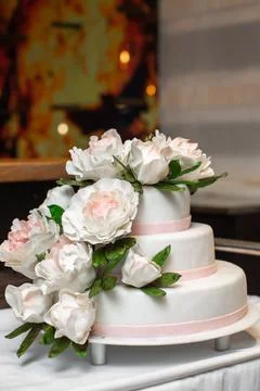Multilevel wedding cake on the table decorated with roses Stock Photos