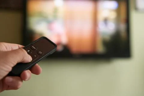 Multimedia streaming concept. Hand holding remote control. TV screen with l.. Stock Photos