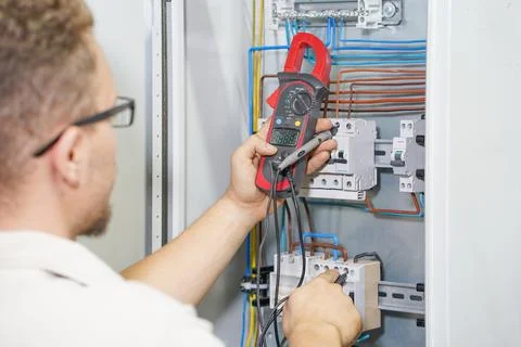 Multimeter is in hands of electrician on background of electrical automation Stock Photos