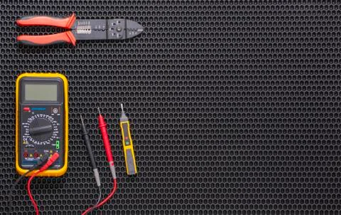 Multimeter, indicator screwdriver and wire stripper on a black rubber mat Stock Photos