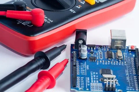 Multimeter with measurement probes and electronics board on a white backgroun Stock Photos