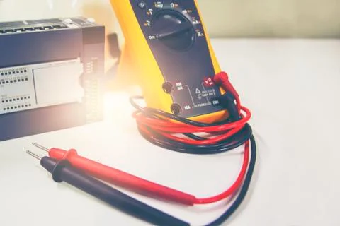 Multimeter with PLC placed on white table. Stock Photos