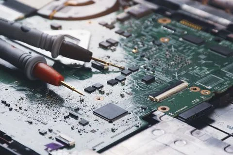 Multimeter probe placed on the motherboard of computer laptop Stock Photos