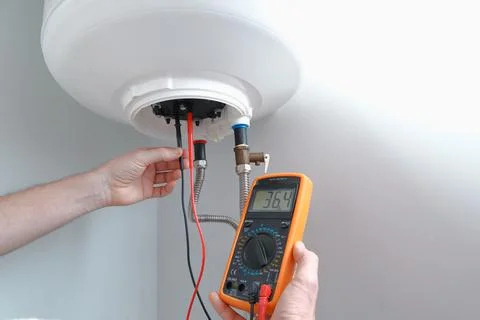Multimeter probes testing heater element. Engineer using a multimeter carryin Foto stock