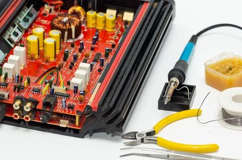 A multimeter with test probes and a circuit board lie on a white background. Foto stock