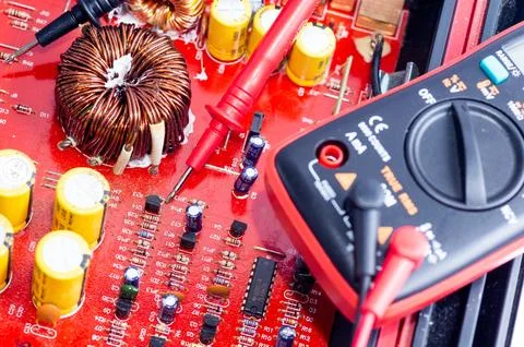 Multimeter with test probes and a circuit board Foto stock