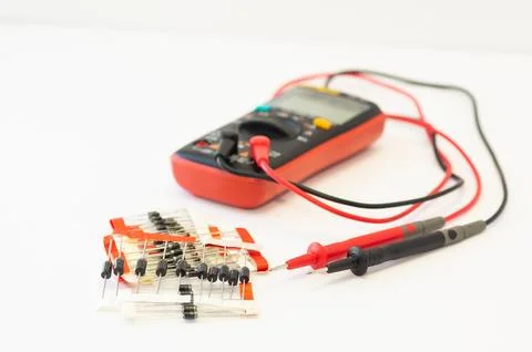 A multimeter with test probes and diodes lies on a white background. Stock Photos