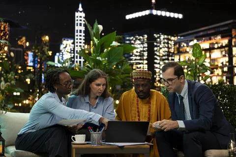 Multinational business professionals evaluate performance metrics on laptop Fotos de archivo