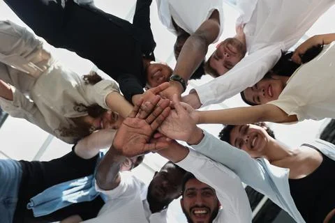 Multinational business team looking down putting hands together Stock Photos