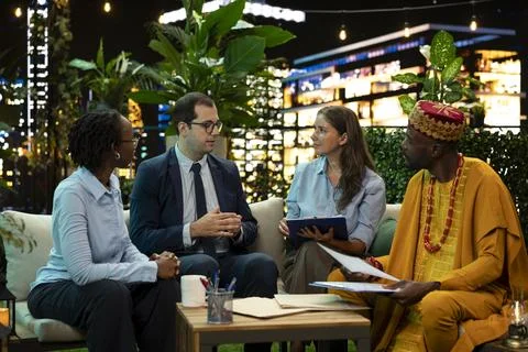 Multinational businesspeople discussing project notes and paperwork on rooftop Stock Photos