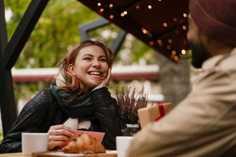 Multinational couple smiling while drinking coffee in cafe outdoors Stock Photos
