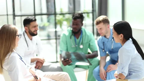 Multinational doctors examine the patient's x-ray. They consult each other. Stock Footage 230920209