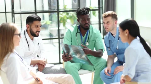 Multinational doctors examine the patient's x-ray. They consult each other. Stock Footage 239024072