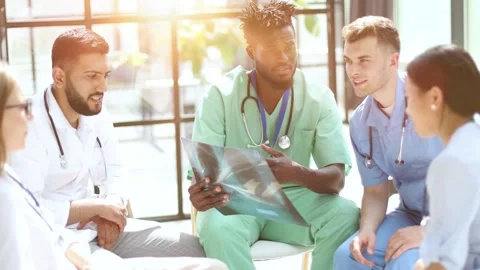 Multinational doctors examine the patient's x-ray. They consult each other. Stock Footage 282524050