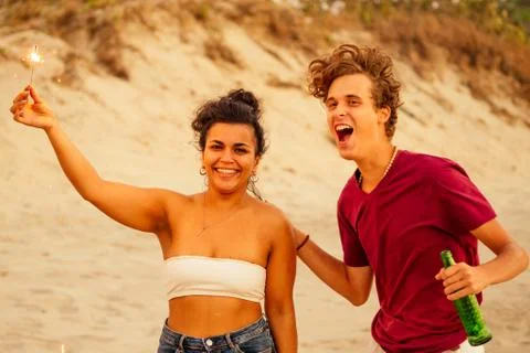Multinational friends dancing and singing with spark stick on ste sandy beach Stock Photos