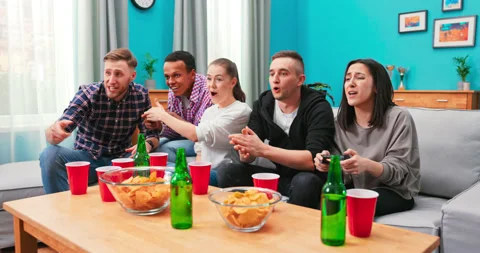 Multinational friends sitting at home on couch and playing video games on 库存影片 152384601