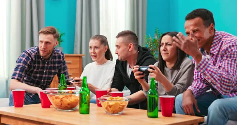 A multinational group of college students sit on the couch and play video games Stock Footage 152380852