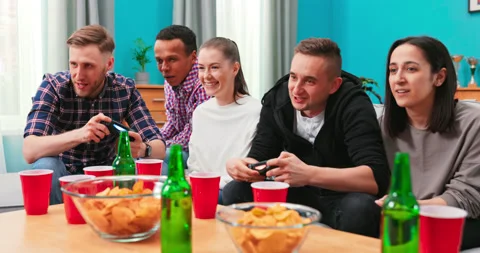 A multinational group of college students sit on the couch and play video games Vidéo 152383286