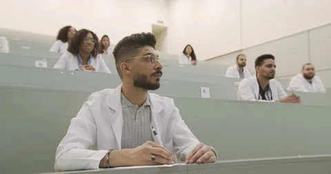 Multinational group of people in white coats attentively listening and making Stock Footage 137564366