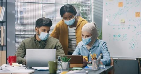 Multinational group of young workers working together on project sitting in Stock Photos