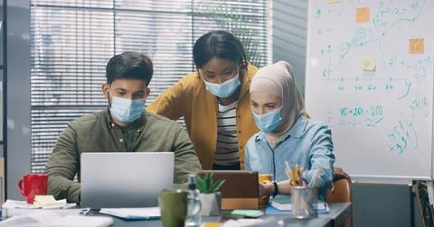 Multinational group of young workers working together on project sitting in Stock Photos