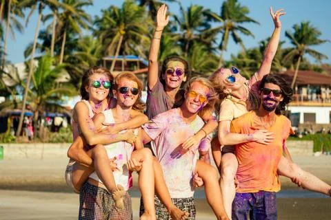 Multinational multicultural mixed race friends in holi dust on beach in Goa Stock Photos