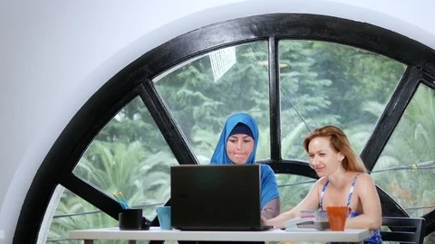 Multinational team concept. Two women, a Muslim woman in a hijab and a Caucasian Stock Footage 114564975