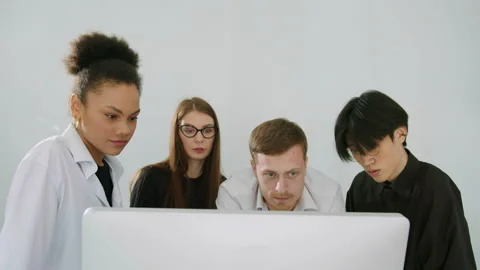 A multinational team studies graphs on a computer screen in the office Stock Footage 246052439