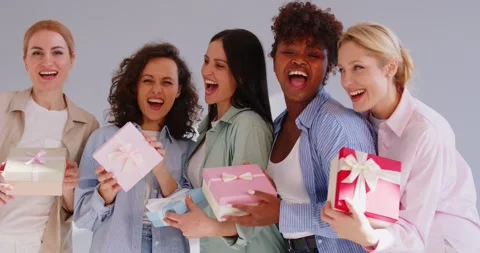 Multinational young women dancing and singing with colorful gift boxes while Stock Footage 323507187