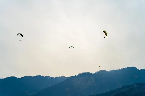 Multipel parasailing gliders against sunset sky and mountains with copy space Stock Photos