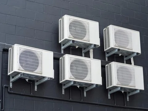 Multiple Air Conditioning Units Mounted on Black Brick Wall Stock Photos