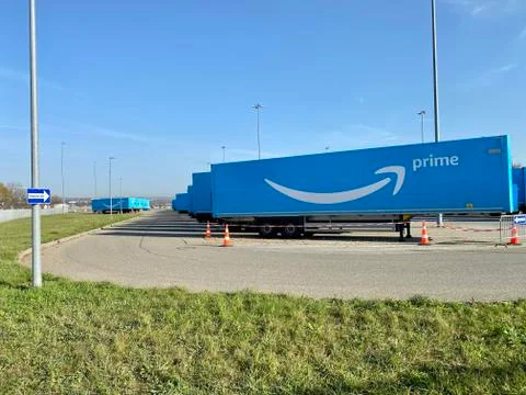 Multiple blue Amazon prime trailers are parked within a waiting are close to the Stock Photos
