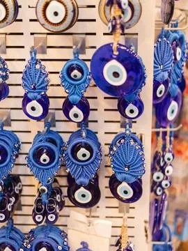 Multiple blue talismans hang on a display at a market. Each piece reflects .. Stock Photos