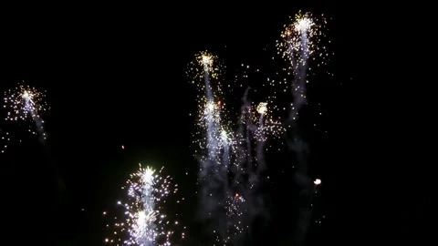 Multiple bright white and golden fireworks burst into black background Stock Footage 328617590