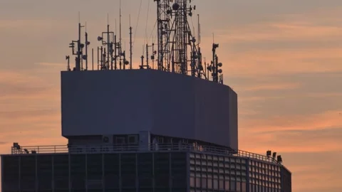 Multiple Broadcasting Antennas on top of High Rise Building at Sunrise Stock Footage 142701050