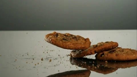 Multiple chocolate chip cookies falling on a reflective surface Stock Footage 327631490