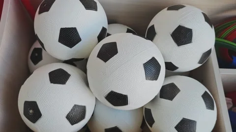 Multiple classic black and white toy soccer balls piled in a wooden box. Sports Vidéo 347073585