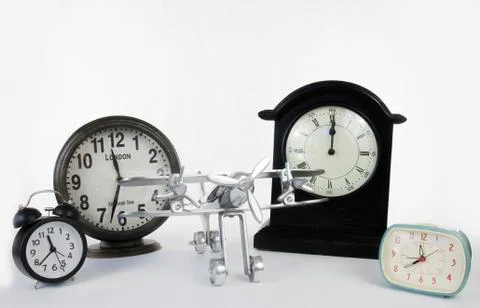Multiple clocks isolated on a white background with metal airplane Fotos Stock