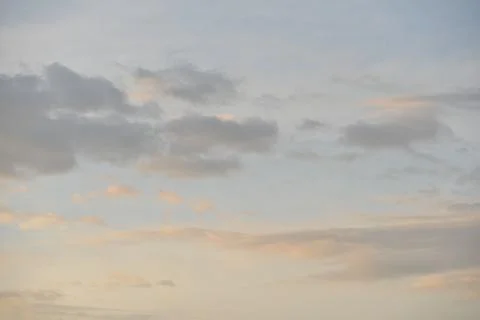 Multiple clouds in a pink, blue and grey sky at sunrise Stock Photos
